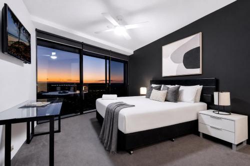 a bedroom with a large white bed and a desk at Circle on Cavill Apartments - Hosted by WowStay in Gold Coast
