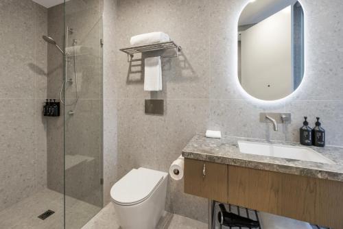 a bathroom with a toilet and a sink and a mirror at Brady Hotels Elizabeth Street in Melbourne