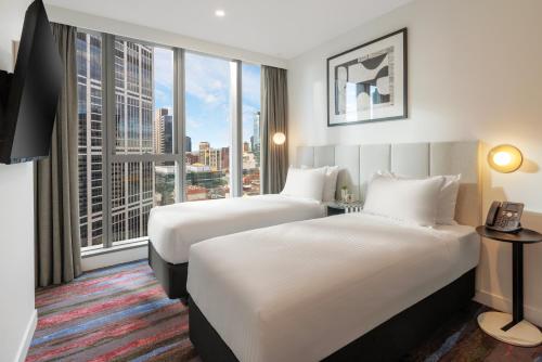 a hotel room with two beds and a large window at Brady Hotels Elizabeth Street in Melbourne