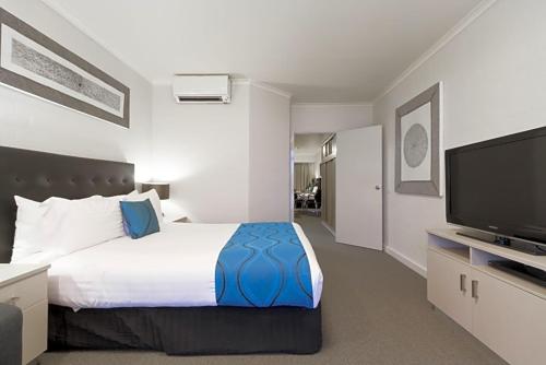 a bedroom with a large bed and a flat screen tv at Pavilion Hotel Wagga Wagga in Wagga Wagga