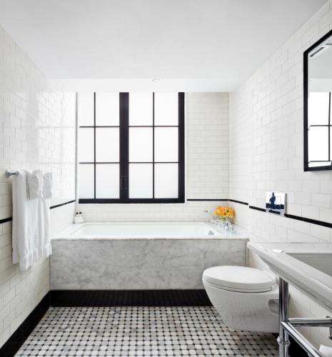 a white bathroom with a tub and a toilet at Walker Hotel Greenwich Village in New York