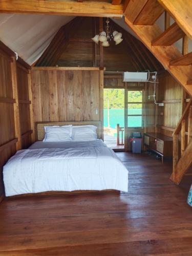 a bedroom with a bed in a wooden house at Selambak View Cottage in Pulau Siantan