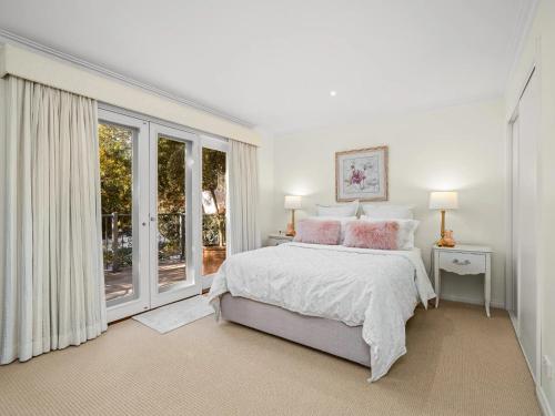 a white bedroom with a large bed with pink pillows at Via Bella Vista in Wangaratta