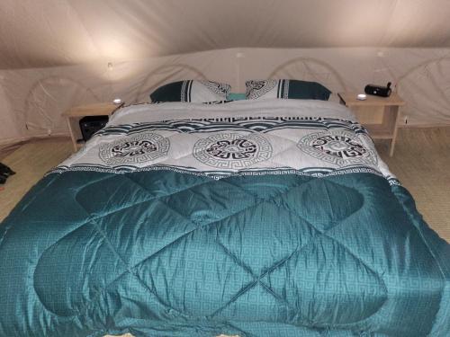 a bedroom with a bed with a blue and white comforter at Ruhondo Campsite View in Muhororo