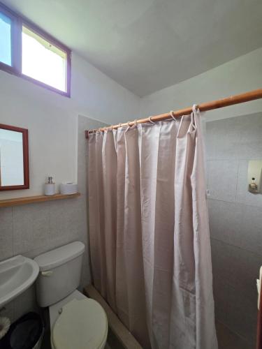 a bathroom with a toilet and a shower curtain at Hostal El Pinzón in Puerto Ayora