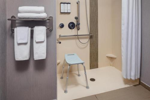 a bathroom with a shower with towels and a stool at Hyatt Place Sumter/Downtown in Sumter