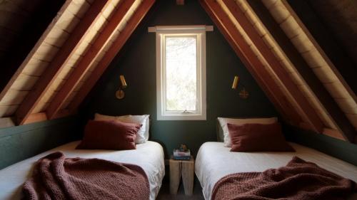 two beds in a room with a window at Burramys in Dinner Plain