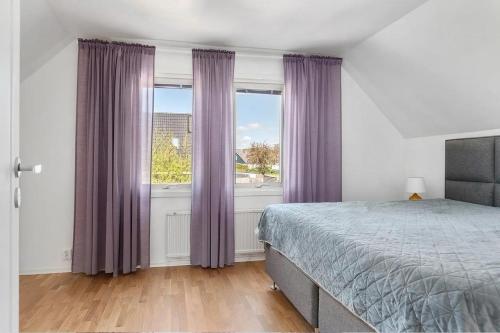 a bedroom with purple curtains and a bed and a window at Villa in Skurup in Skurup