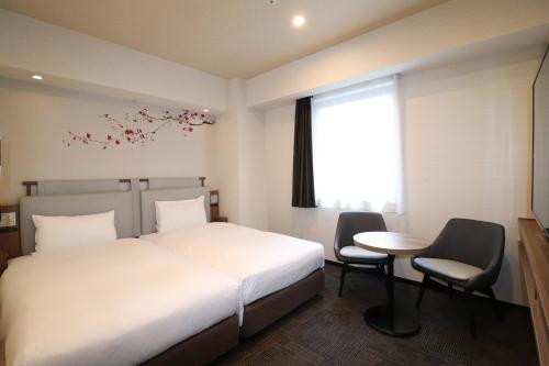 a bedroom with a bed and a table and chairs at Via Inn Hakataguchi Ekimae in Fukuoka