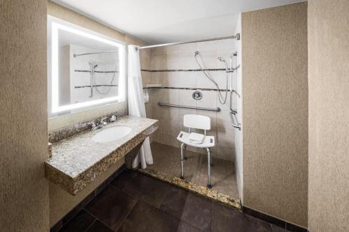 a bathroom with a sink and a mirror and a chair at Wingate by Wyndham Little Rock in Little Rock