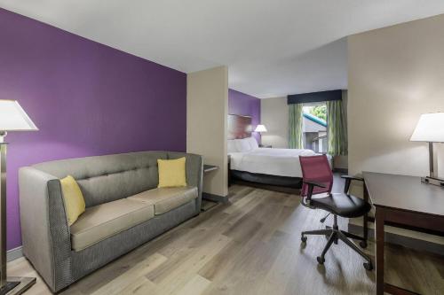 a hotel room with a couch and a bed at La Quinta Inn & Suites by Wyndham Louisville East in Louisville