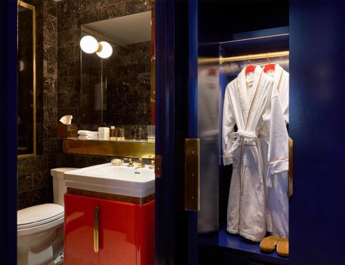a bathroom with a sink and a robe on a door at The Manner, The Unbound Collection by Hyatt in New York