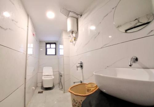 a white bathroom with a sink and a toilet at Hotel Sunrise in Ahmedabad