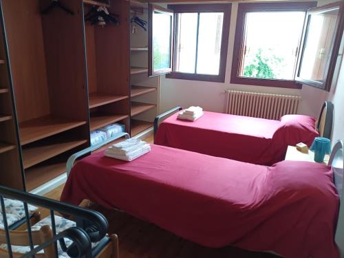 two beds in a room with pink sheets and windows at Corte Maria in Vicenza