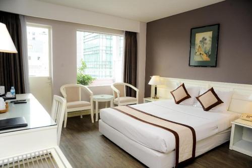 a hotel room with a large white bed and a desk at Saigon Star Hotel in Ho Chi Minh City