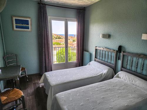 a bedroom with two beds and a window at Hôtel AMBEILLE Vue Mer in Collioure