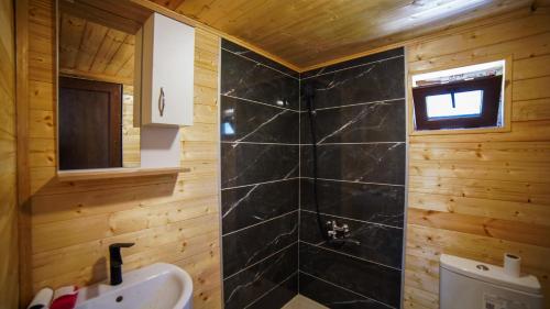 a bathroom with a black tiled shower and a sink at SkyGona Alpine Retreat in Ghebi