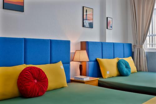 a room with a bed with blue and yellow pillows at Hanoi Sihouse Eco in Hanoi