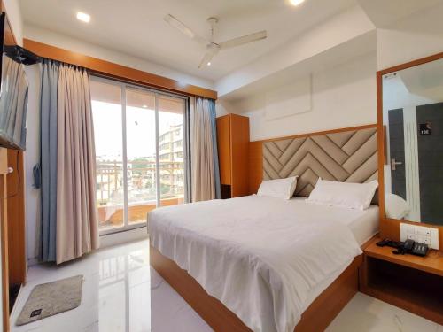 a bedroom with a large bed and a large window at Lions Hotel Adidev in Badlapur