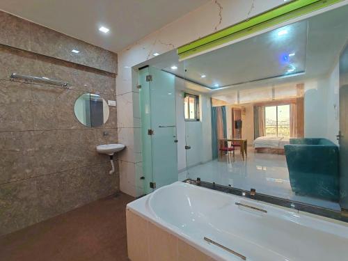 a bathroom with a large mirror and a tub at Lions Hotel Adidev in Badlapur