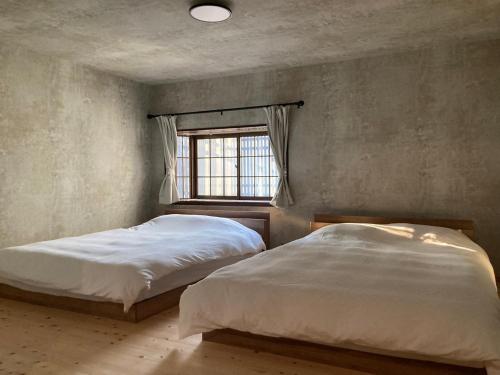 two beds in a bedroom with a window at Deer Path Nara in Nara