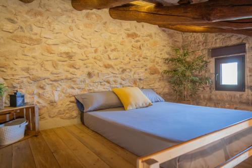 a bedroom with a bed in a stone wall at Can Rata in Tivenys