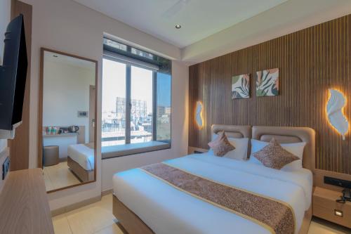 ein Schlafzimmer mit einem weißen Bett und einem großen Fenster in der Unterkunft Hotel 7 skye in Surat