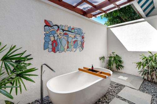 a bath tub in a bathroom with a painting on the wall at Emana Aruna in Toyapakeh