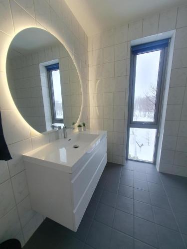 a white bathroom with a sink and a mirror at Great villa with amazing view in Tromsø