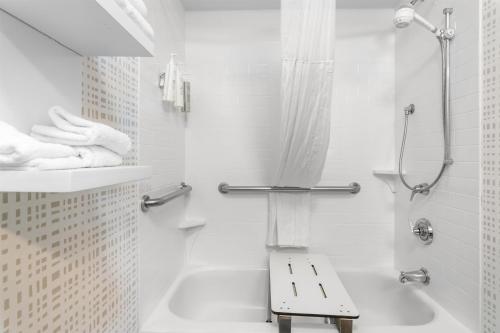 a white bathroom with a shower and a bench at Hampton Inn Portage in Portage
