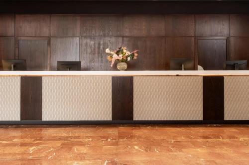 a long counter with a vase of flowers on it at Hilton Strasbourg in Strasbourg