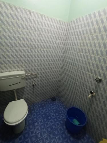 a small bathroom with a toilet and a bucket at Dmello guesthouse in Palolem