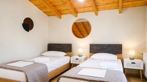 two beds in a room with white walls and wooden ceilings at Isidoros House in Keramoti