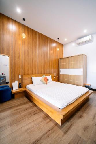 a bedroom with a large bed with a wooden wall at Coto Center Homestay in Đảo Cô Tô