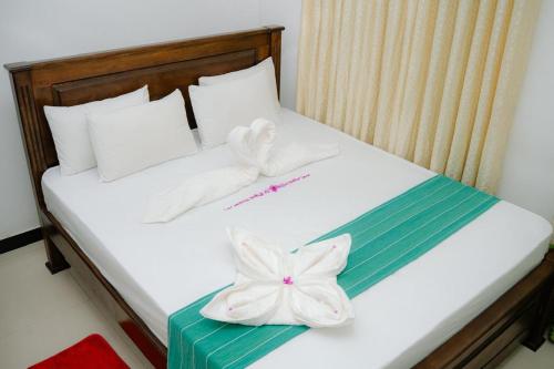 a bed with white towels and a flower on it at Kiula Resort in Hambantota