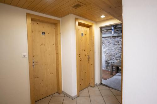 two wooden doors in a room with a stone wall at Chasa Macun in Schleins