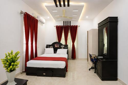 a bedroom with a bed with red curtains and a television at Heaven Stay in Varkala