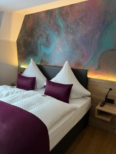 a bedroom with a bed with purple and white pillows at Hotel Restaurant Wolfsschlucht GmbH in Bad Münstereifel