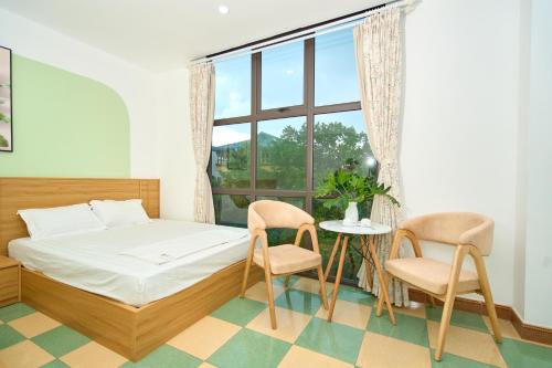 a bedroom with a bed and two chairs and a window at Sunny - Việt House in Kỳ Vĩ
