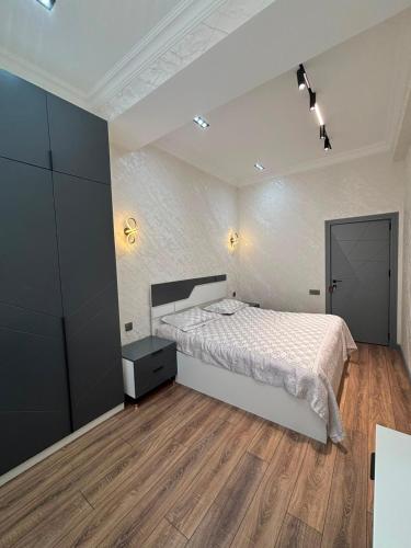 a bedroom with a white bed and a wooden floor at Huzur tapacaginiz ev in Sumqayıt