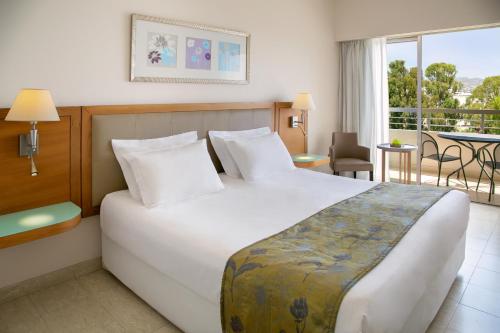 a hotel room with a large bed and a balcony at Atlantica Miramare Beach in Limassol