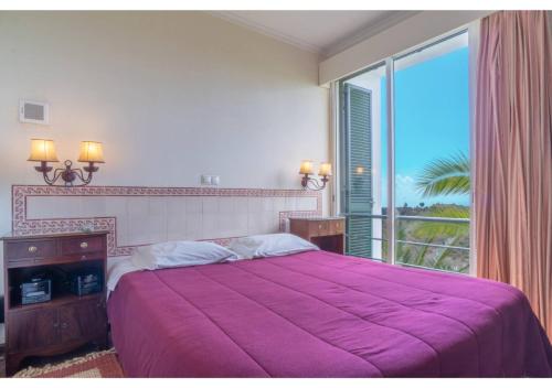 a bedroom with a large purple bed with a large window at Villa Amelia in Caniço