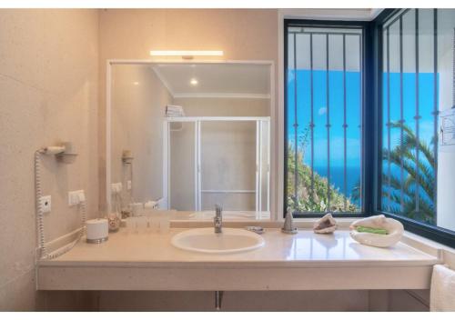 a bathroom with a sink and a large window at Villa Amelia in Caniço
