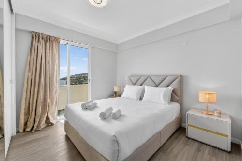 a white bedroom with a large bed and a window at Calheta Atlantic Pearl in Calheta