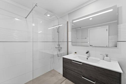 a white bathroom with a sink and a shower at Calheta Atlantic Pearl in Calheta