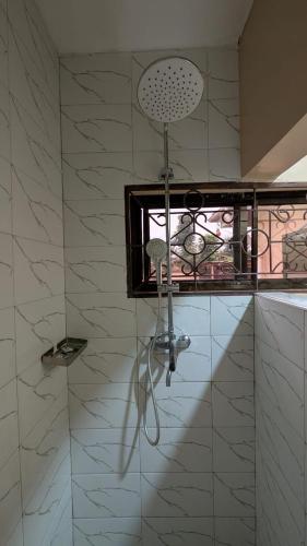 a shower with a shower head in a bathroom at Kivulini Homes in Moshi