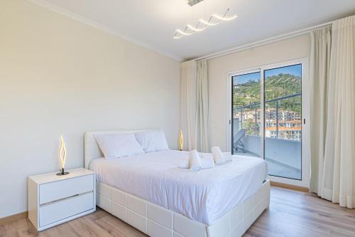 a white bedroom with a large bed and a window at Sunflower Apartment in Caniço