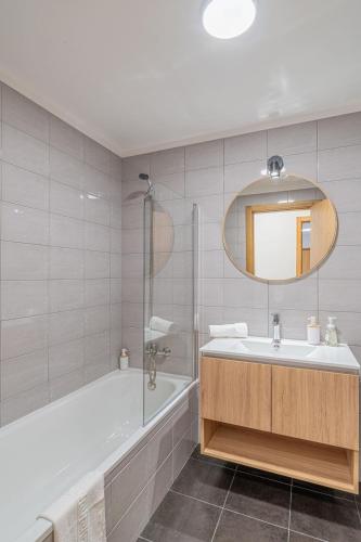 a bathroom with a tub and a sink and a mirror at Sunflower Apartment in Caniço