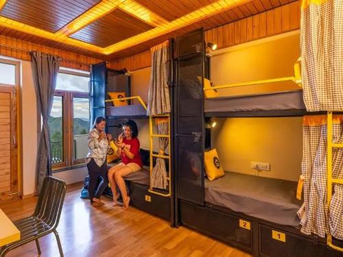 a group of people sitting in a room with bunk beds at The Hosteller Chakrata in Chakrāta