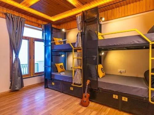 a room with three bunk beds and a guitar at The Hosteller Chakrata in Chakrāta